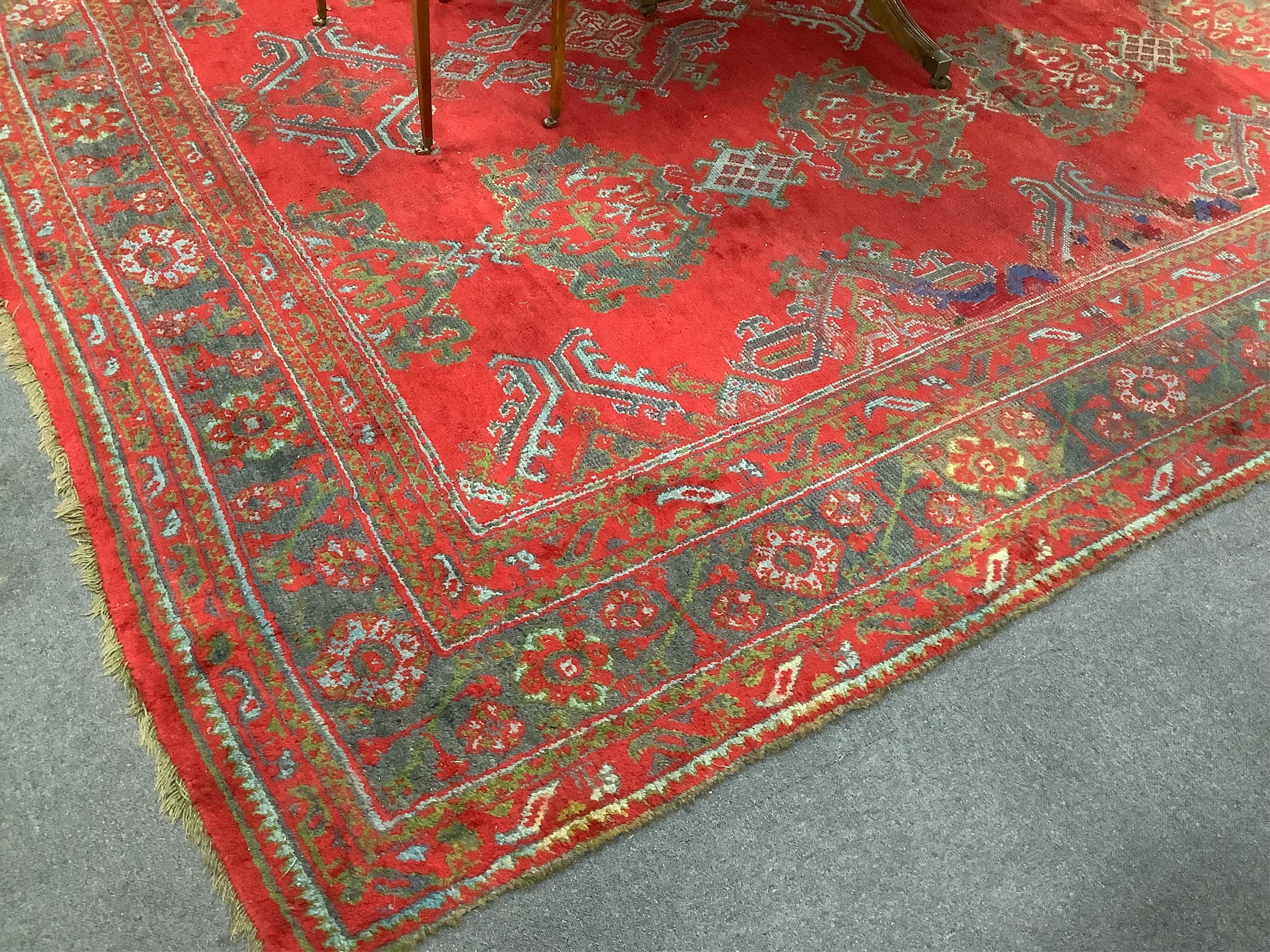 A large Turkish carpet, with triple row of stylised medallions on a red ground, multi bordered, 413 x 345cm. Condition